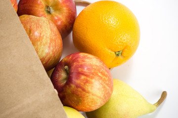 apples and pears in a paper bag of craft paper on white background. Free space for your text. Top view.