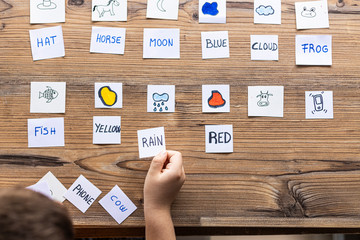  Little kid playing with cards of words and pictures.