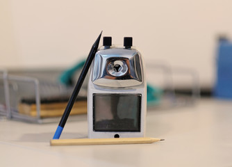 Pencil sharpener and two pencils. Focus on pencil sharpener.