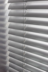 Aluminum blinds. Made from metal. Venetian blinds closeup on the window. Silver color. Closed horizontal blinds in sunny day. Modern sun protection and window decoration.