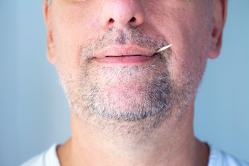 Obraz premium White man with toothpicks in his mouth. Grinning grin with barely grown gray beard