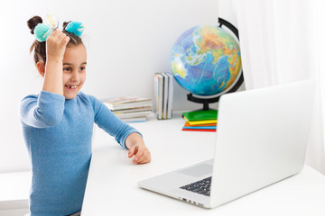 education, school, technology and internet concept - little student girl pointing at laptop pc with light bulbs at school