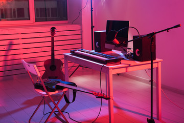 Microphone, computer and musical equipment guitars and piano background. Home recording studio concept.