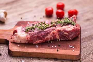 Fresh raw meat for steak on wooden cutting board.