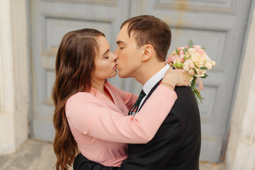 Happy bride and groom kiss near church door. Wedding concept.