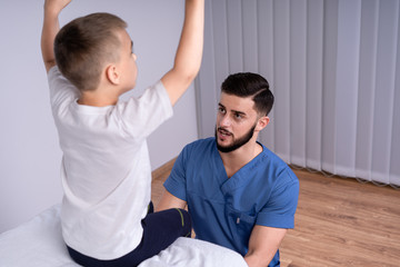 Fototapeta premium Boy sits on a special couch, beside him, sat the doctor in the form of doctors, concept of treatment and rehabilitation