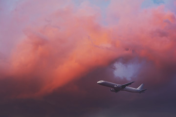 Commercial airplane flying through clouds in dramatic sunset light. Travel concept