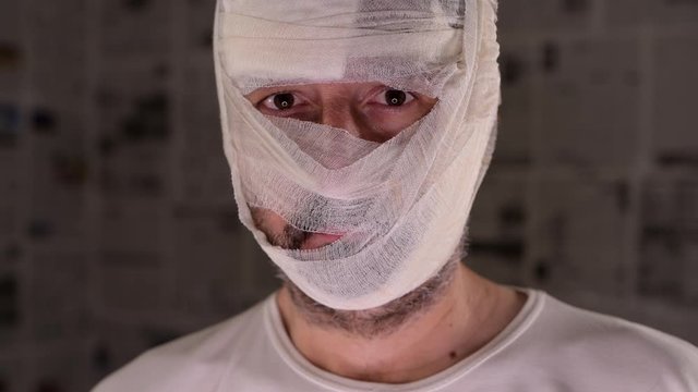 Victim of tabloid journalism and fake news infodemic, conceptual image of man wrapped in bandages surrounded by walls covered with daily newspaper pages