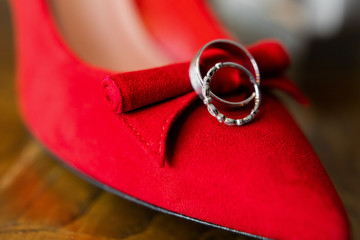 Wedding rings on red shoes of the bride.