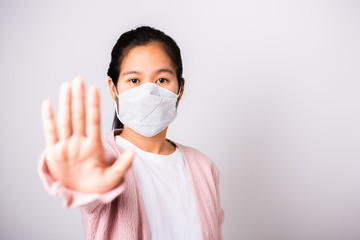 Asian woman wearing surgical protection face mask hygiene against coronavirus her raising hand stop sign, studio shot isolated on white background with copy space, COVID-19 or corona virus concept