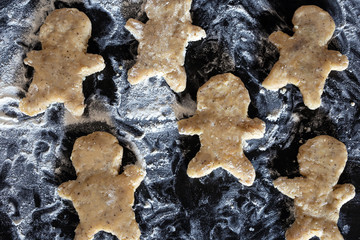 Person baking Gingerbread man cookies, Person hands in dough with flower in cozy kitchen