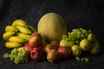 fruits cabbage banana melon grape orange apples pear a dark background. health vegetarianism