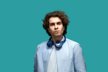 I command you! Portrait of serious young beautiful man wearing white t-shirt and blue shirt in headphones looking at camera with anger