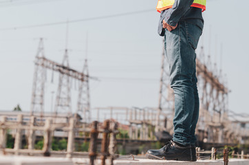 electrical engineer stands at the construction site beside the electrical substation, the side view of the lower part of the body.