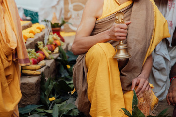 young Brahman Brahmachari holds a bell in his hands during Yagya a fire flame ritual of hindu pooja performating during sacred traditional Vedic ceremony.