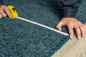 worker measures the carpet for restoration and cleaning.