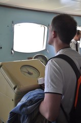 Young man standing at the device in the wheelhouse of the ship and looking through the porthole © Ольга Толкачева