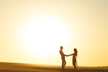 Newlyweds walk barefoot on the sand in the white desert