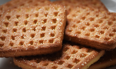 Shortbread brown homemade shortbread from the oven. Cookies are square in shape, flat with a hole, yellow, beige and brown.