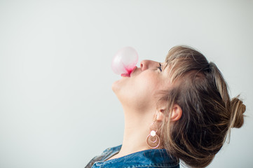 profile view of a blonde woman making a bubble gum with her head up. Great copy space.