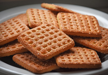 Shortbread brown homemade shortbread from the oven. Cookies are square in shape, flat with a hole, yellow, beige and brown.