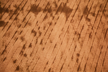 Aerial view of big brown field with trails from agricultural machinery