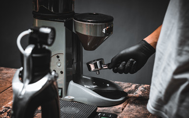 Coffee grinder grinding freshly roasted make beans with background coffee grinder.