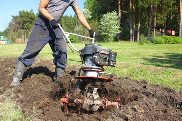 Man plows ground with motor cultivator.
