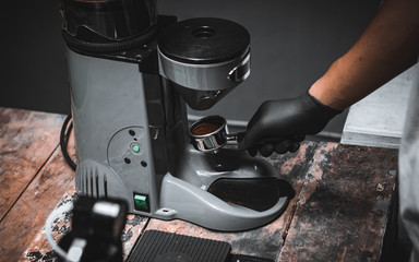 Freshly ground coffee beans in a portafilter by the coffee grinder in coffee shop.