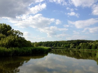 Fototapeta na wymiar Lake With Reflection By Trees Against Sky