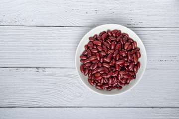 Dried Red beans or kidney beans in white bowl on white wood background. top view.