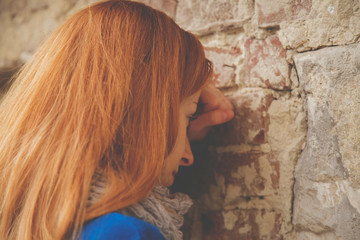 Portrait of beautiful sad woman leaning on the wall as symbol of hopelessness, depression and frustration.
