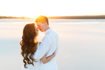 groom hugging bride in the desert at sunset