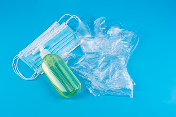 protective medical blue mask, disposable gloves and a green bottle with an antiseptic on a blue background