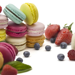 Multicolored macaroons on a white background with strawberries, raspberries, mint and blueberries