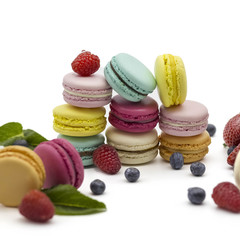 Multicolored macaroons on a white background with strawberries, raspberries, mint and blueberries