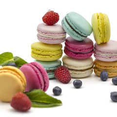 Multicolored macaroons on a white background with strawberries, raspberries, mint and blueberries