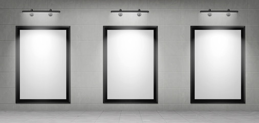 Blank movie posters illuminated by spotlights. Vector realistic mockup of white picture in black frames on gray tiled wall in cinema, theater hallway or gallery. Empty advertising banners with lamps
