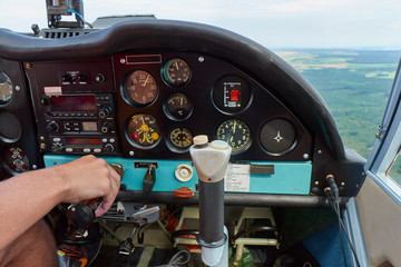 Close up of a man in a cockpit piloting small four seat airplane, pushing buttons on control panel...