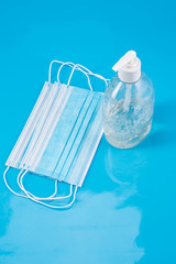 protective medical blue mask and a transparent bottle with an antiseptic on a blue background