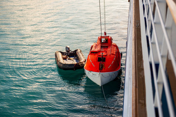 Lowering orange lifeboat to water in Arctic waters, Svalbard. Abandon ship drill. Lifeboat...
