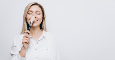 A pretty young woman is using different make-up accessories for application of make-up