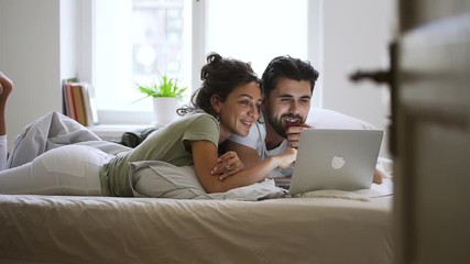 Happy married caucasian couple using laptop at home Spbd. man and woman watching movies, browsing internet, searching. concept technology, communication, husband. resting at home - Powered by Adobe