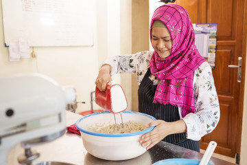 happy muslim woman homemade baking. bakery owner mixing some dough