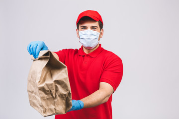 Delivery man employee in red cap blank t-shirt uniform face mask gloves hold empty cardboard box isolated on white background. Service quarantine pandemic coronavirus virus 2019-ncov concept.