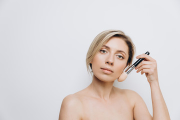 A pretty young woman is using different make-up accessories for application of make-up