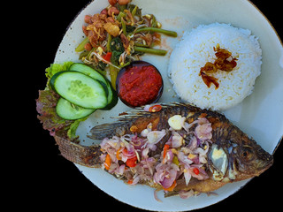 Balinese dish - Tilapia fish fry with rice and vegetables with black background