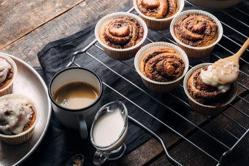 Cooking of homemade cakes. Sweet pastries on a wooden table with a cup of coffee and milk. Home Cinnabon. View from above. Rustic