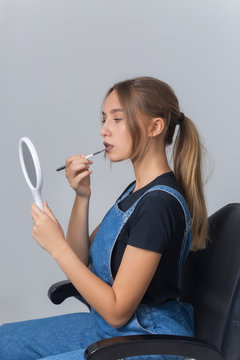Young beautiful woman lipstick with an applicator looking in mirror.