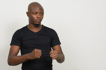 Stressed young bald African man with fists raised